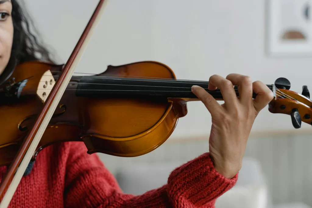 A woman skillfully playing the violin indoors, focusing on her hand positioning.