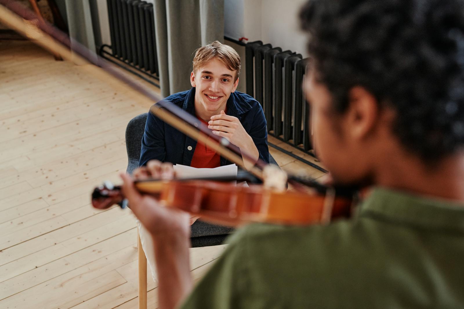 A joyful music lesson with two young men playing and learning the violin indoors.