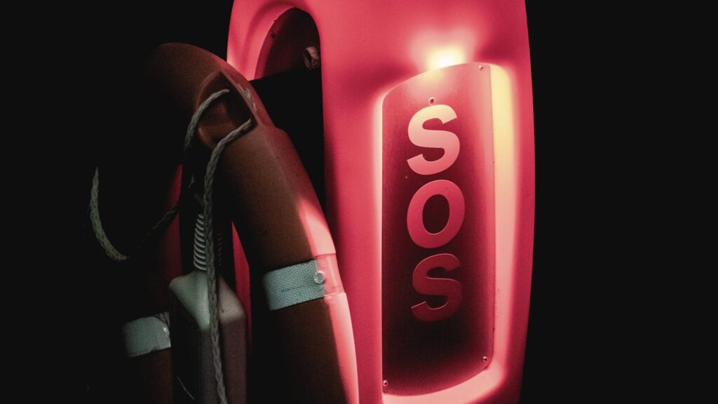 Close-up of an illuminated SOS lifebuoy for emergency rescue at night.