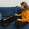 a woman opening a violin case while sitting on a couch